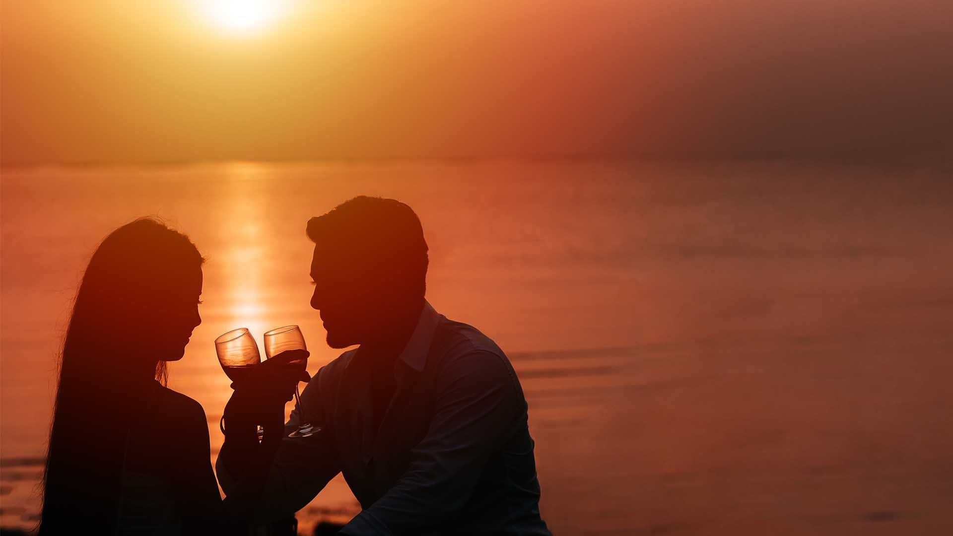 תמונות אווירה זוג עם כוסות יין על רקע שקיעה